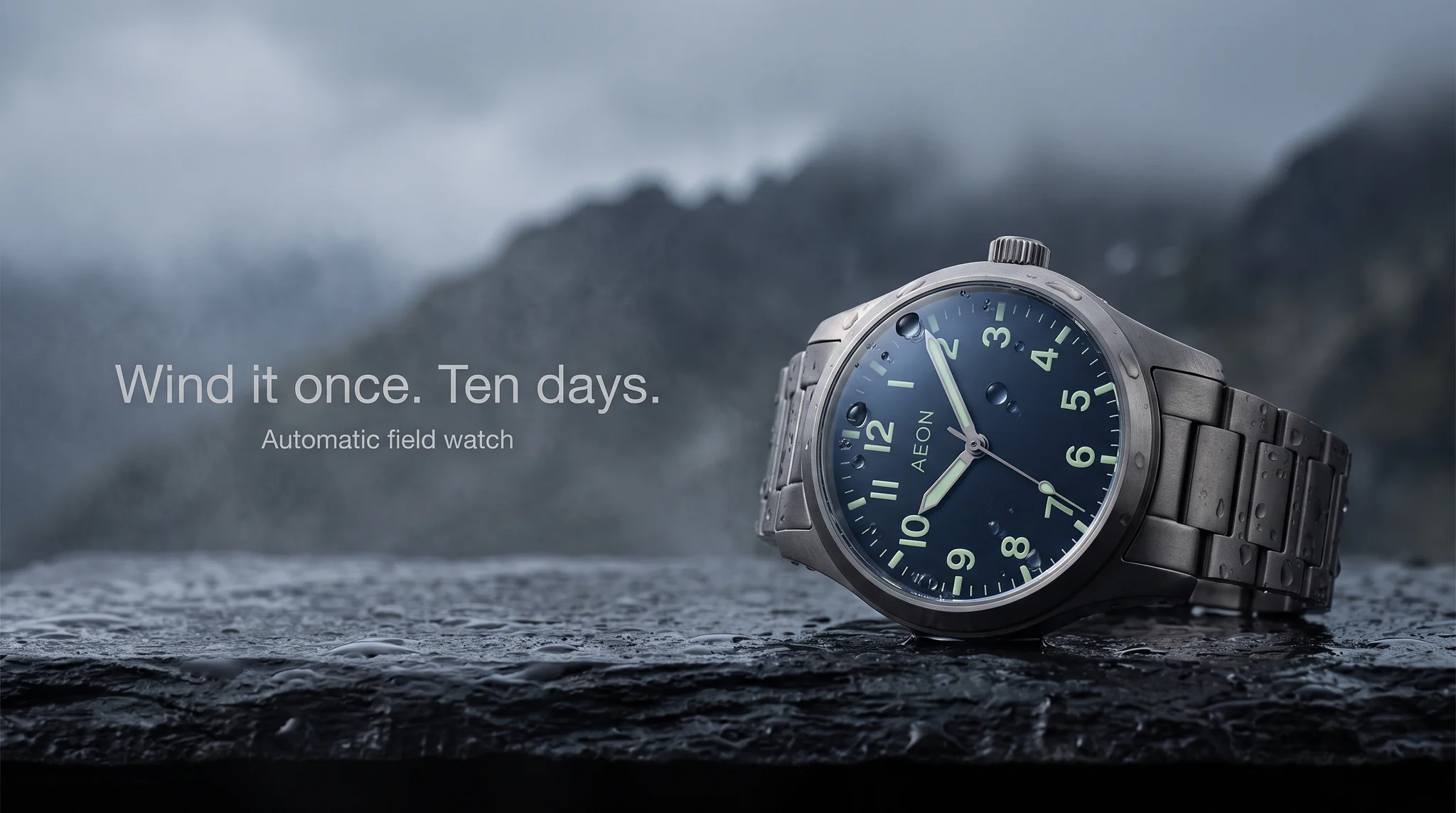 Example ad generated with terrads: AEON titanium field watch on a rain-dark slate ledge before an alpine ridge, headline “Wind it once. Ten days.”